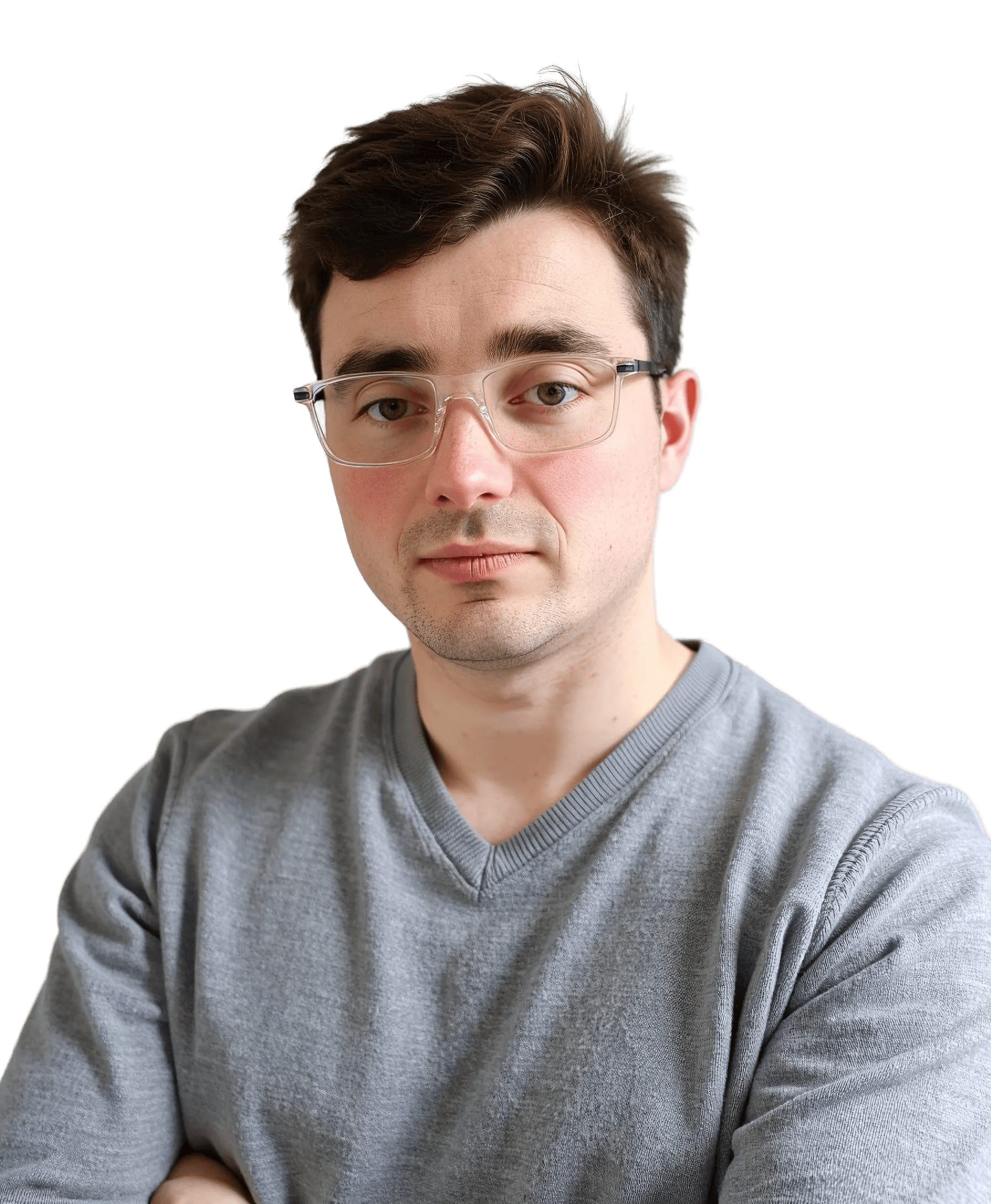 A man with short brown hair and glasses wearing a gray sweater stands with his arms crossed, looking directly at the camera against a plain background.